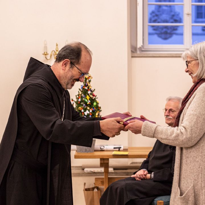 Benediktinerabt Michael Reepen überreicht Carola Holzmann ein Faksimile des Lektionars der Benediktsregel.